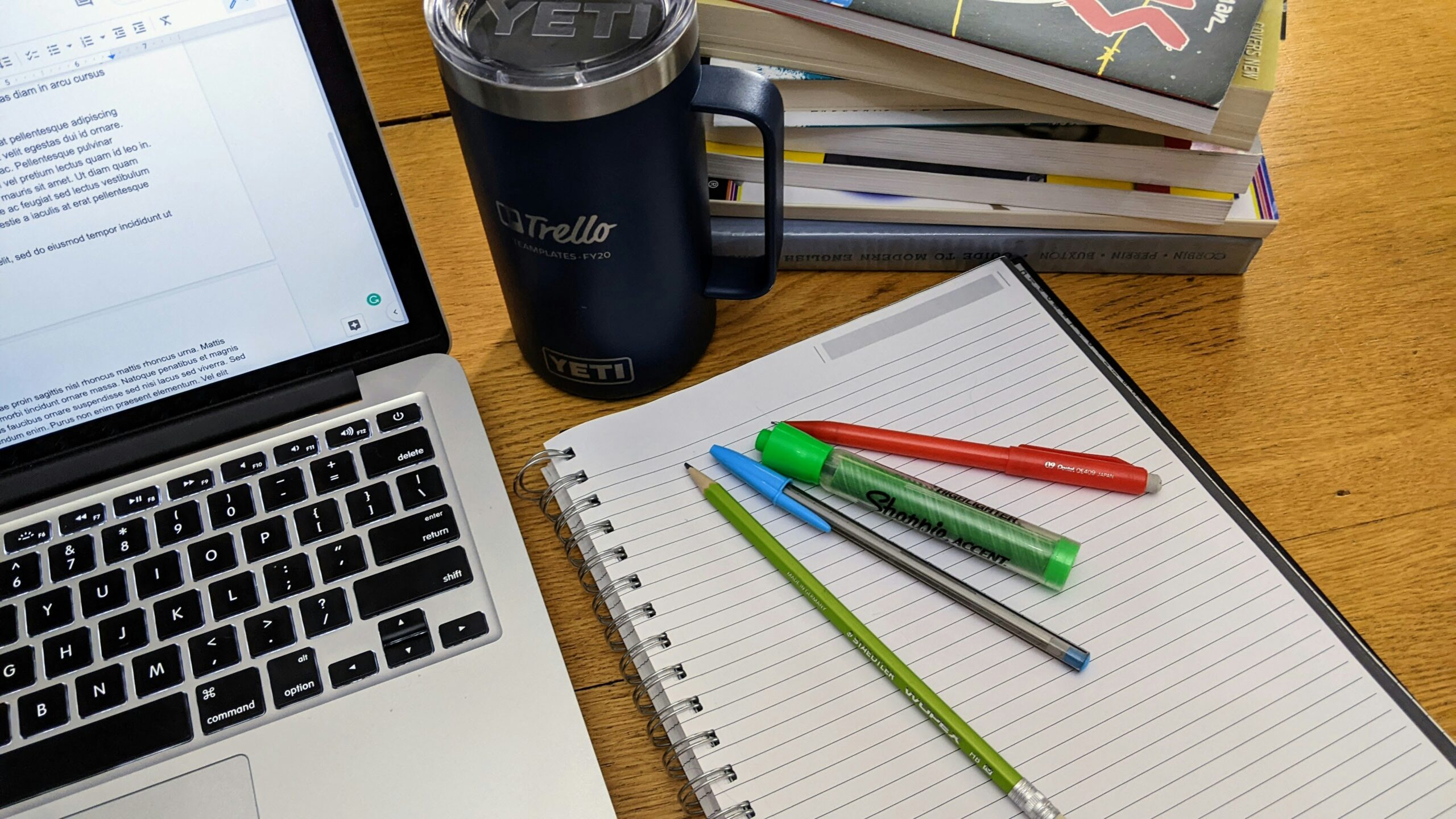 机の上にパソコンとノート、ペン、コーヒーが置かれているイメージ画像